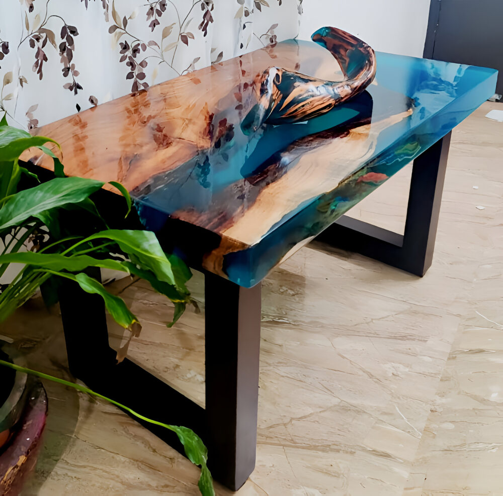 A wooden coffee table with a resin-infused, teal-blue top and dark-brown metal legs sits on a light beige floor.