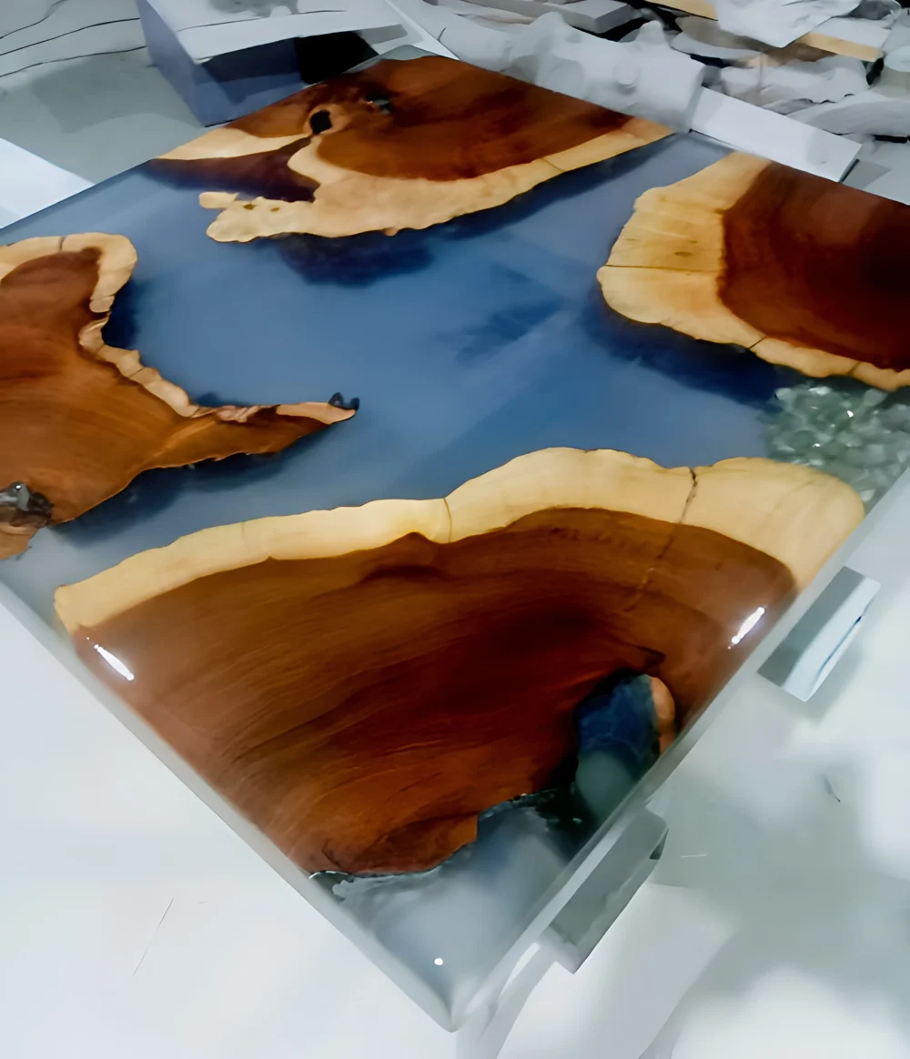 A beautifully crafted resin coffee table featuring a striking combination of natural wood and deep, oceanic blue resin
